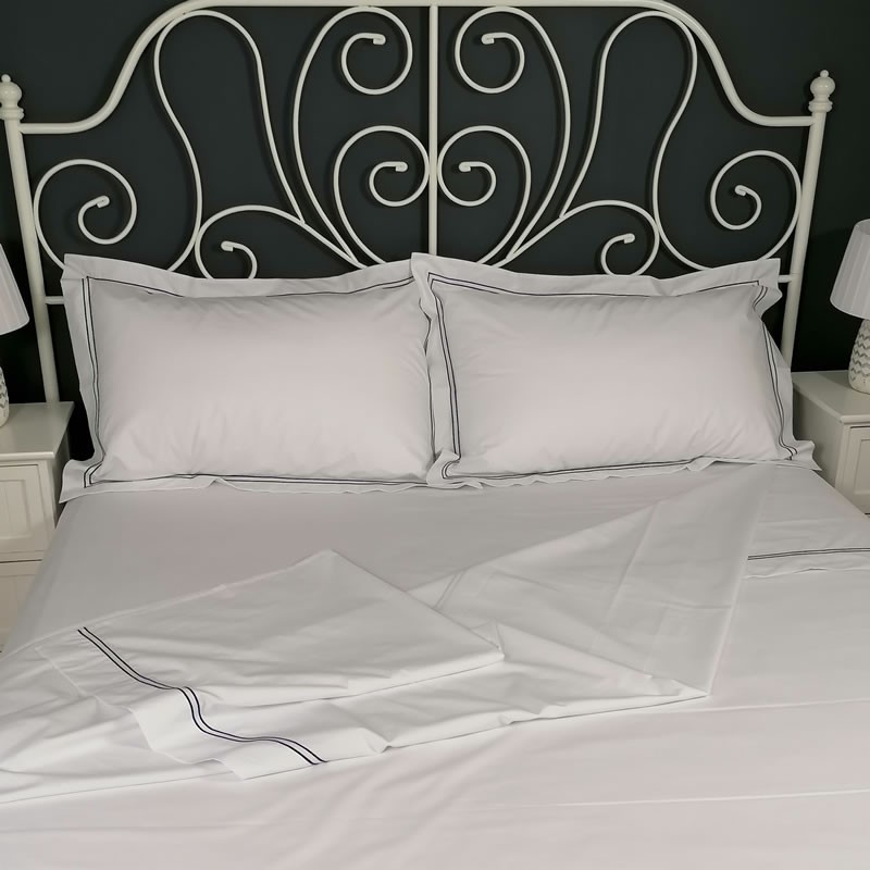 Flat sheet blue trim Egyptian Cotton 200 Thread Count Percale Porto laid out on bed Flat sheet blue trim Egyptian Cotton 200 Thread Count Percale Porto laid out on bed